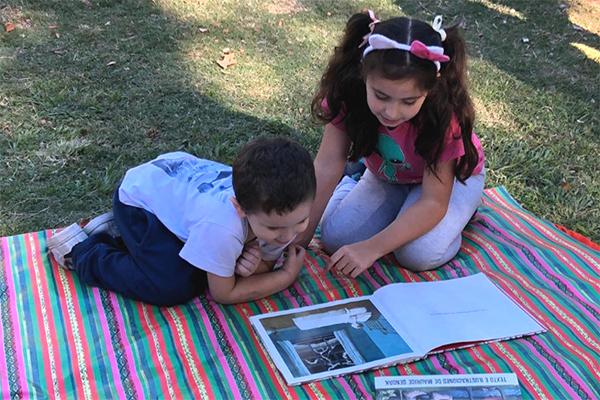 Niños leyendo un libro en el parque