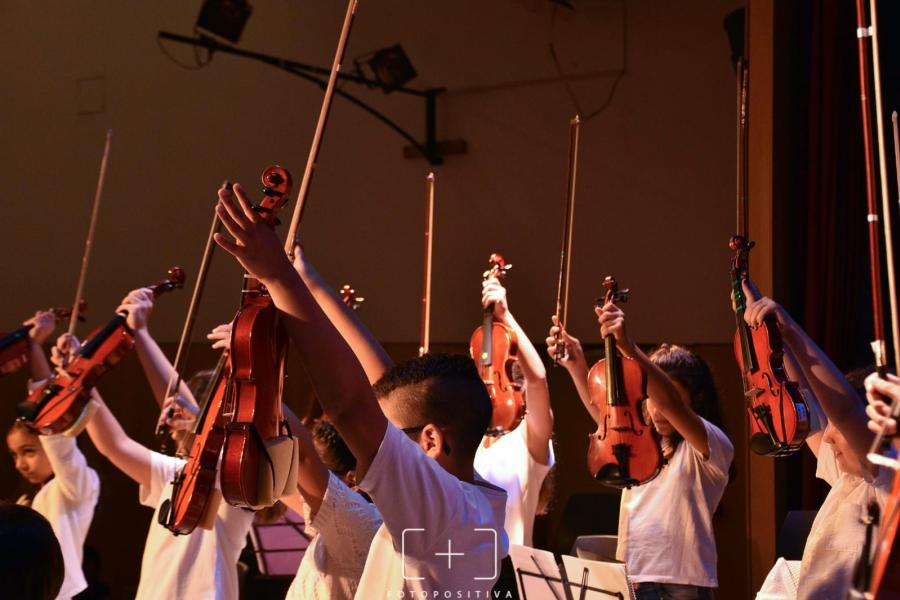 Orquesta levandanto los violines en señal de saludo al público