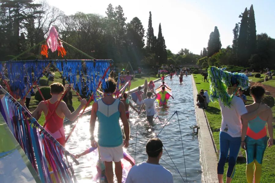 Artistas ingresando a una fuente de agua del parque independencia con barriletes