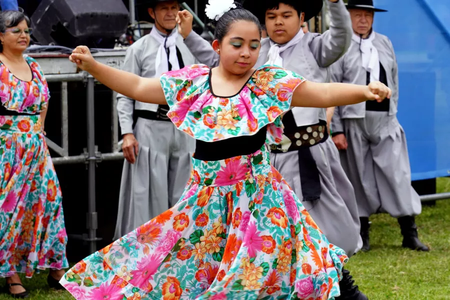 Joven bailando danza folclórica. Con una flor en su cabello y un vestido colorido.