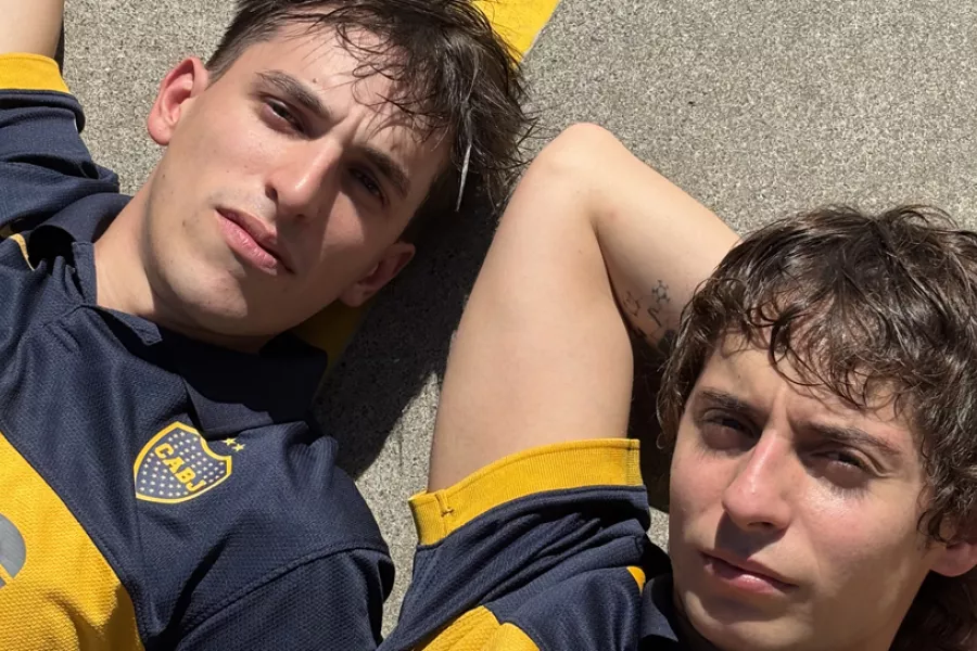 Dos actores con camisetas de boca recostados al sol