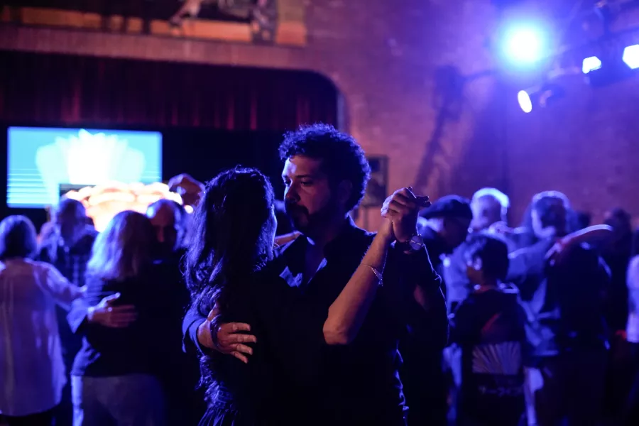 Es una imagen sobre una milanga, en dónde más cerca se ve una pareja bailando tango y más lejos, diferentes parejas haciendo lo mismo