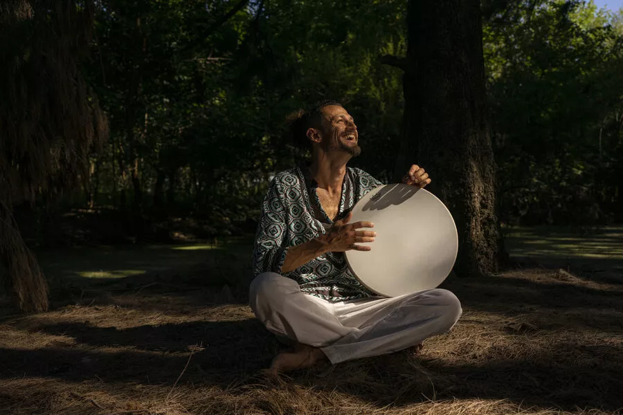 Es la imagen de un músico tocando un instrumento en un lugar con muchos árboles