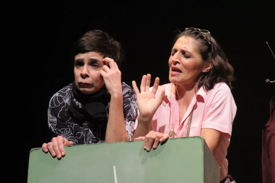 Escena de una obra de teatro en donde se observa dos personas actuando 