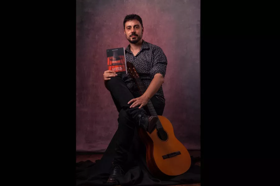 Foto de Facundo Madrid sosteniendo su libro “La guitarra del tango en Rosario”.