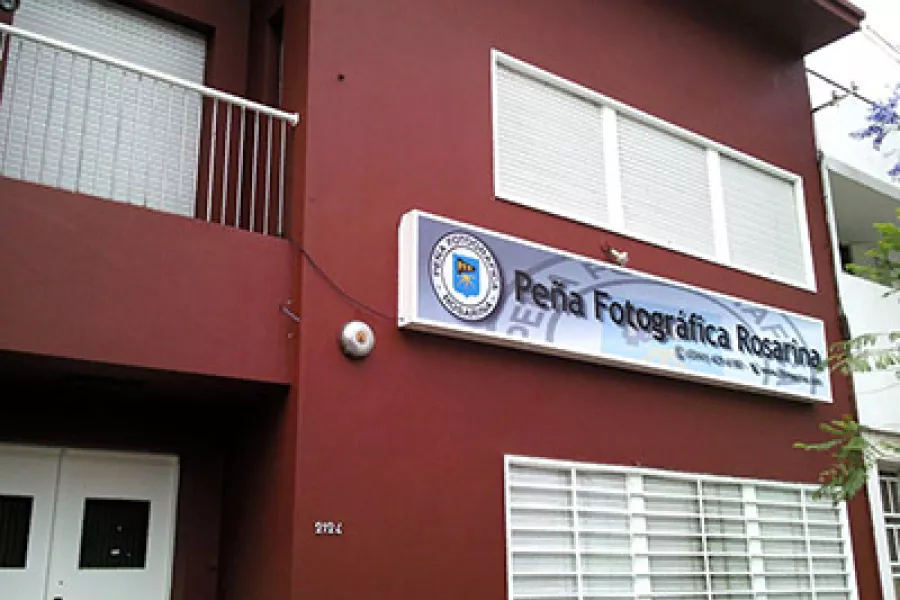 Es el frente de un edificio pintado de color bordo, con detalles blancos
