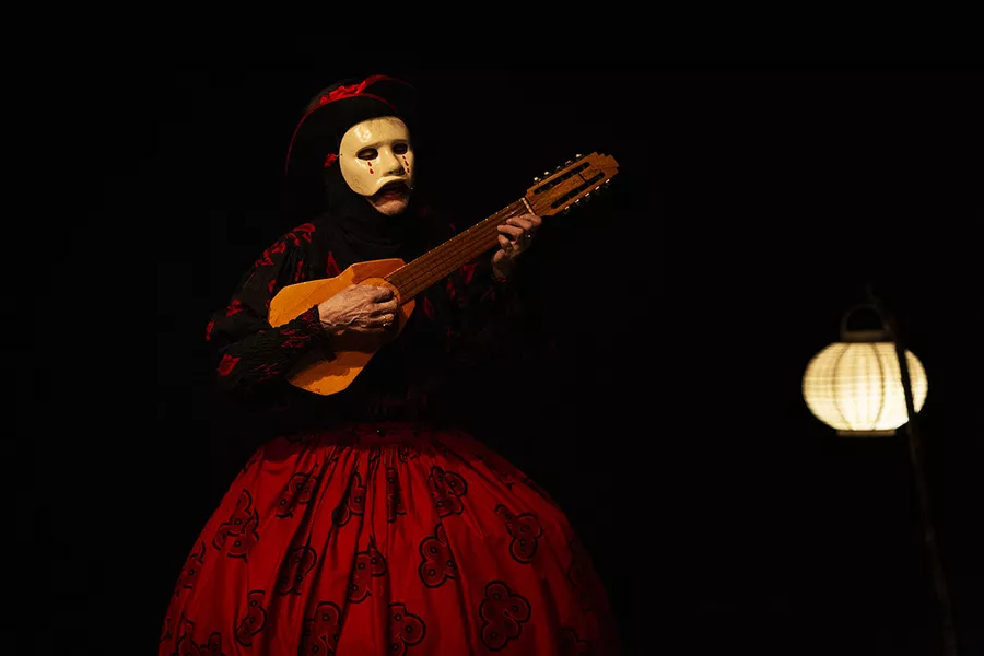 Esla imagen de una persona con un vestido rojo y negro tocando un instrumento de cuerdas