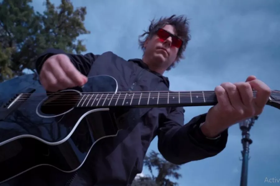 Es la imagen de un músico tocando una guitarra