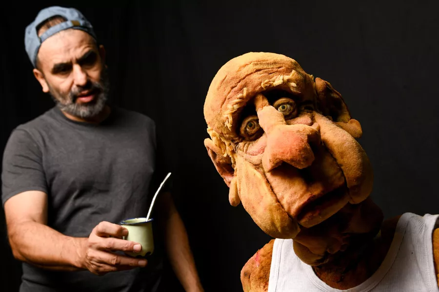 Es la imagen de una persona que le está ofreciendo un mate a un titere 