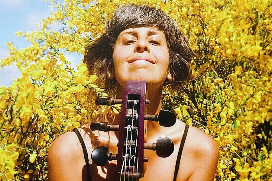 Es la imagen de la cantautora sosteniendo un instrumento musical llamado violonchelo