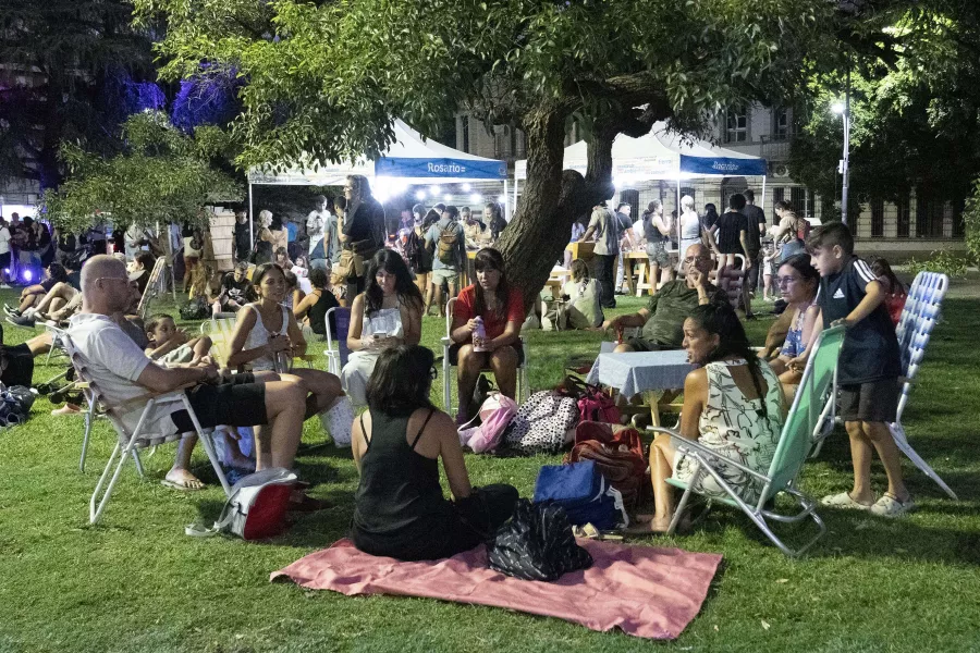 Grupo de jovenes, adultos y niños sentados en ronda. Algunos en reposeras otros en mantas sobre el pasto. Se encuentran conversando.