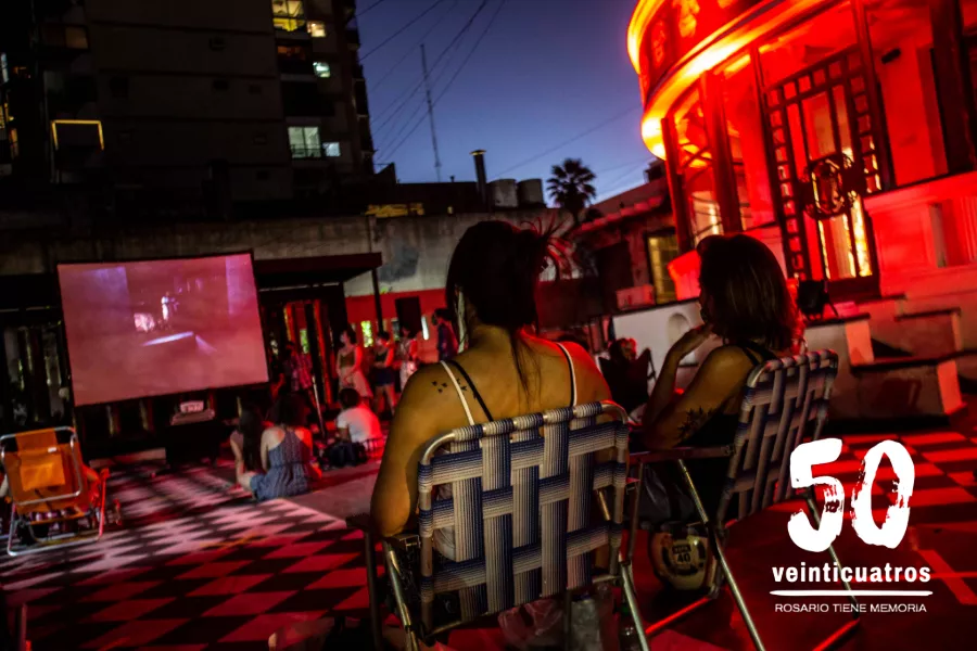 Dos personas sentadas en una reposera, mientras miran una pelicula en la terraza del museo de la memoria