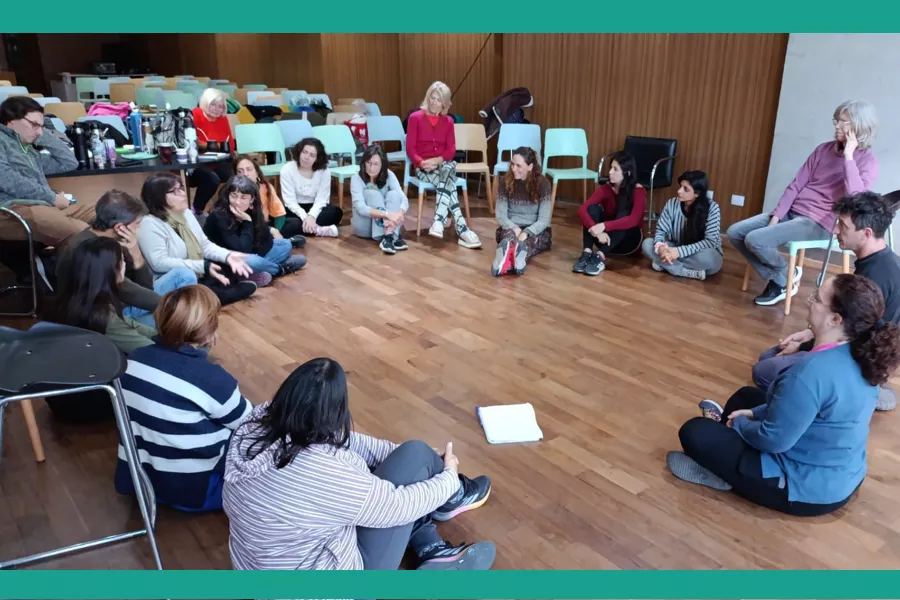 Un grupo de gente sentada en ronda en el piso, en la Sala Angélica Gorodischer.