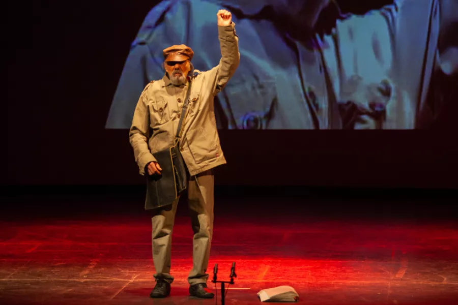 Retrato de Naum Krass sobre el escenario con el puño en alto