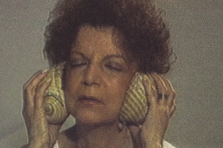 Mujer apoyando caracoles en sus orejas