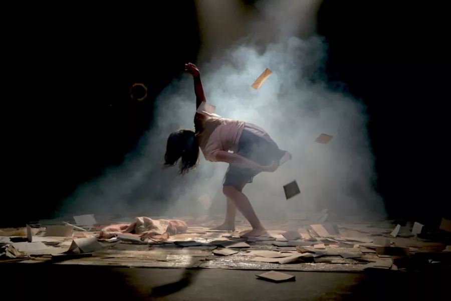 Protagonista en escena rodeada de cartas que caen desde arriba