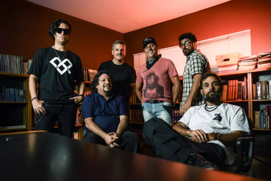 Es la imagen de una banda de rock. Hay dos músicos sentados y 4 parados