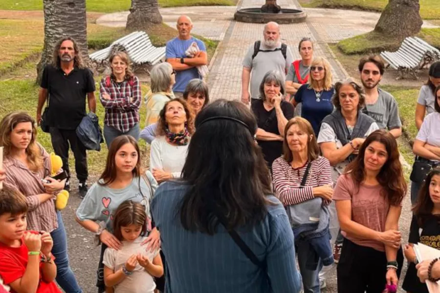 La mediadora de espalda a la cámara recibe a un grupo de visitantes del Museo de la Ciudad, al fondo se observa un sector del Parque de la independencia.