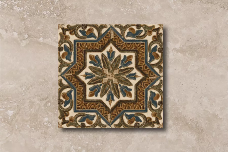Sobre un fondo de piedra color beige se encuentra un cerámico con ornamentación geométrica basada en una estrella de ocho puntas y motivos florales que complementan los espacios libres en colores marfil, azul, verde y marrón.