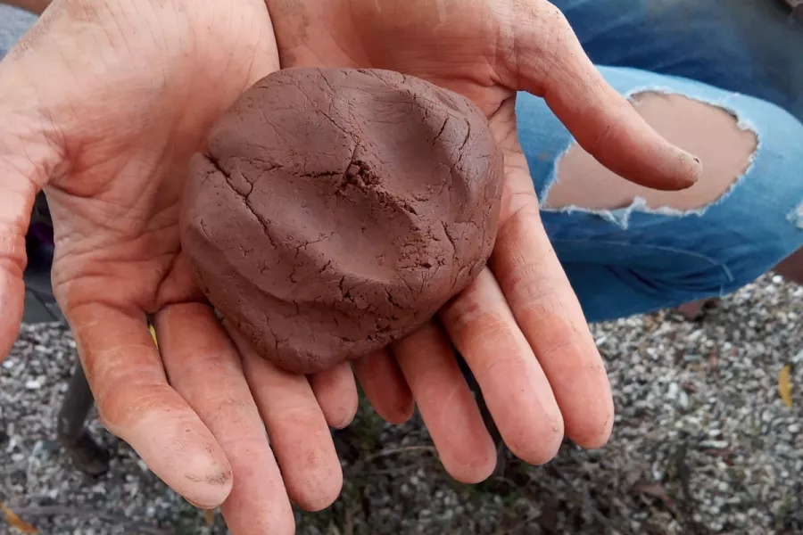 dos manos juntas en primer plano sostienen arcilla preparada para ser moledada