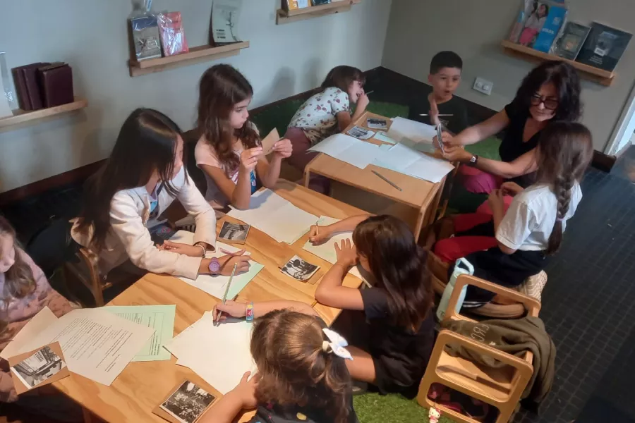 Un grupo de niñas y niños leen y escriben alrededor de una mesa en el interior del Museo