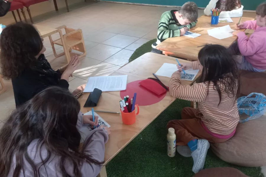 Infancias escriben sobre una mesa en el Espacio Invernadero.