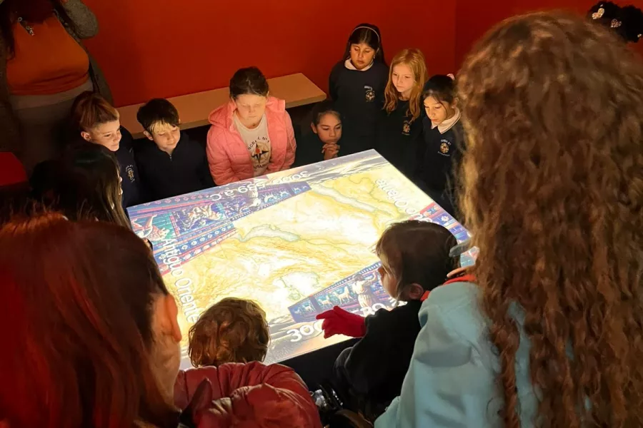 Un grupo de niñas y niños observan con atención el mapping de la sala 1 de la muestra La Ruta de los Azulejos