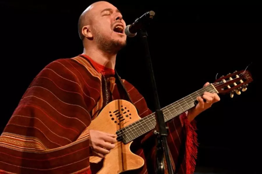 Es la imagen de un cantante vestido con un poncho y una guitarra
