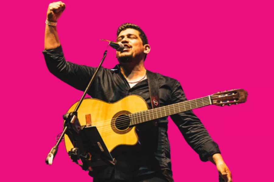 Es la imagen de un cantautor que está cantando una canción, con una guitarra criolla y un fondo magenta