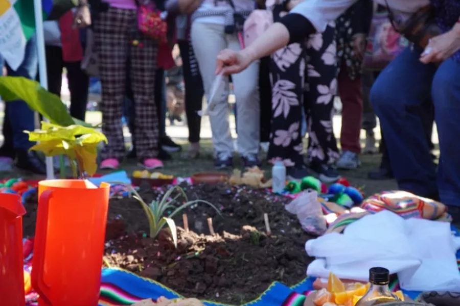 Personas conmemorando la Pachamama en un ritual con ofrendas