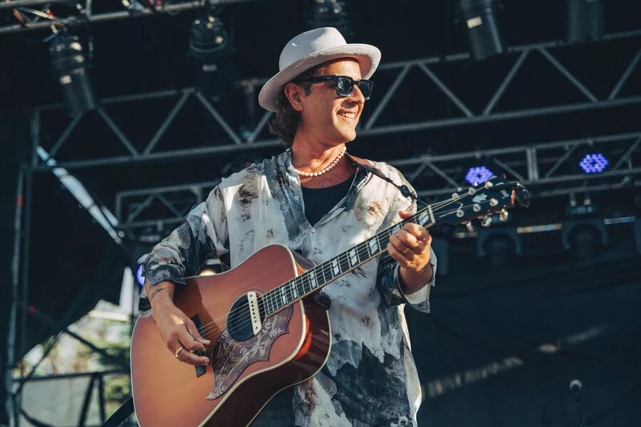 Es la imagen de un cantante tocando la guitarra. En la misma tiene un sombrero y una camista blanca