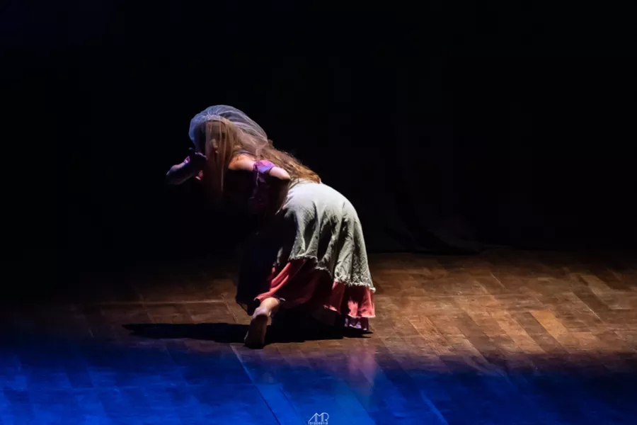 Es la imagen de una bailarina haciendo una coreo en un piso de madera