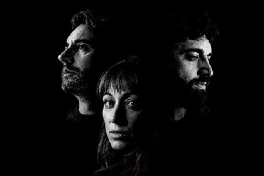 Es la imagen de dos actores y una actriz posando para un poster en un fondo negro