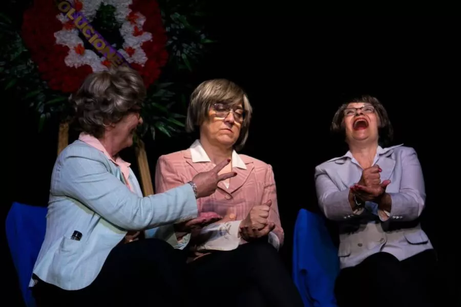 Es la imagen de tres actrices caracterizadas como ancianas que están sentadas y haciendo una escena