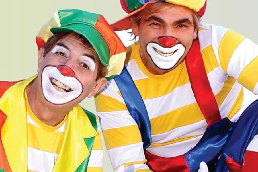 Es la imagen de dos payasos con un remera blanca y amarilla y maquillados 