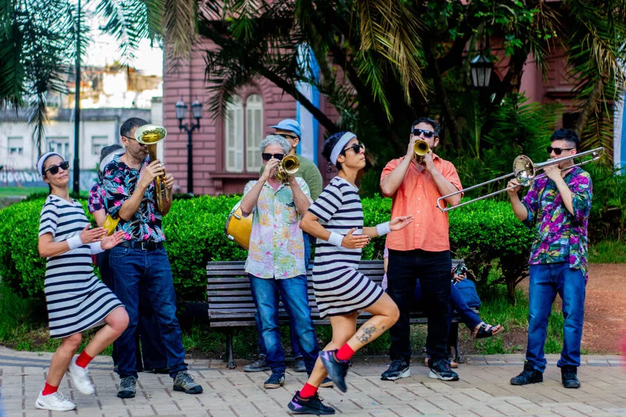 Es la imagen de un grupo de artistas realizando una intervención en una plaza, con instrumentos y con movimientos