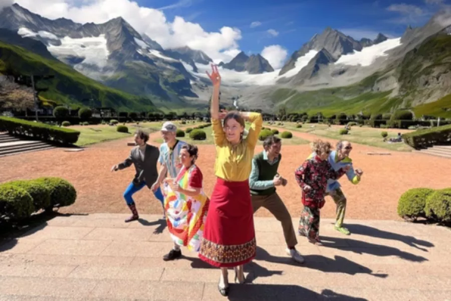 Es la imagen de un grupo de actrices y actores caracterizados como ciudadanos/as suizos/as en medio de los Alpes