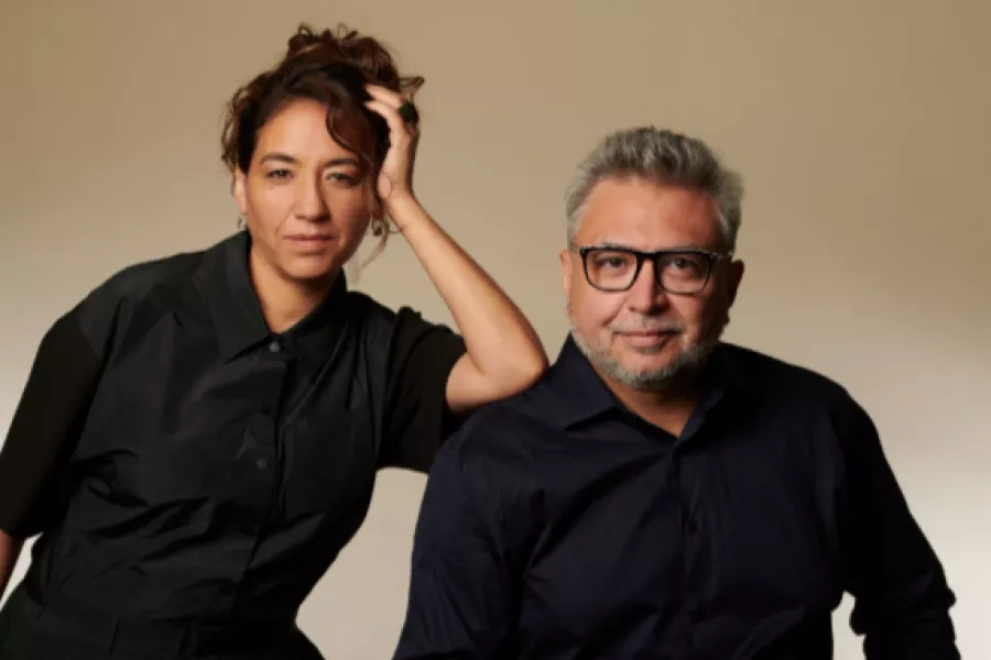 Es la imagen de una actriz y un actor posando para una fotografía: están vestidos de negro