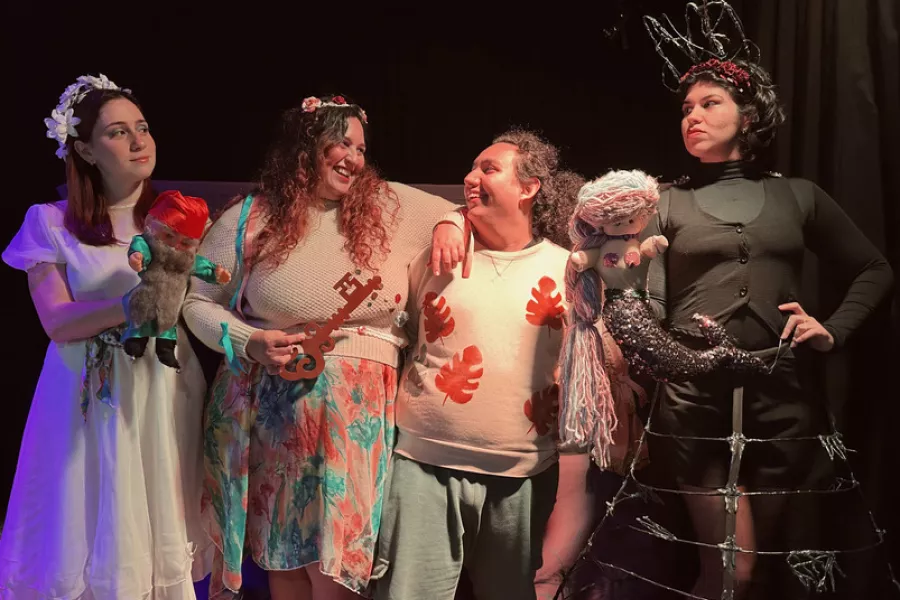 Es la imagen de un grupo de actrices caracterizadas como sus personajes: tiene vestidos y vinchas de colores