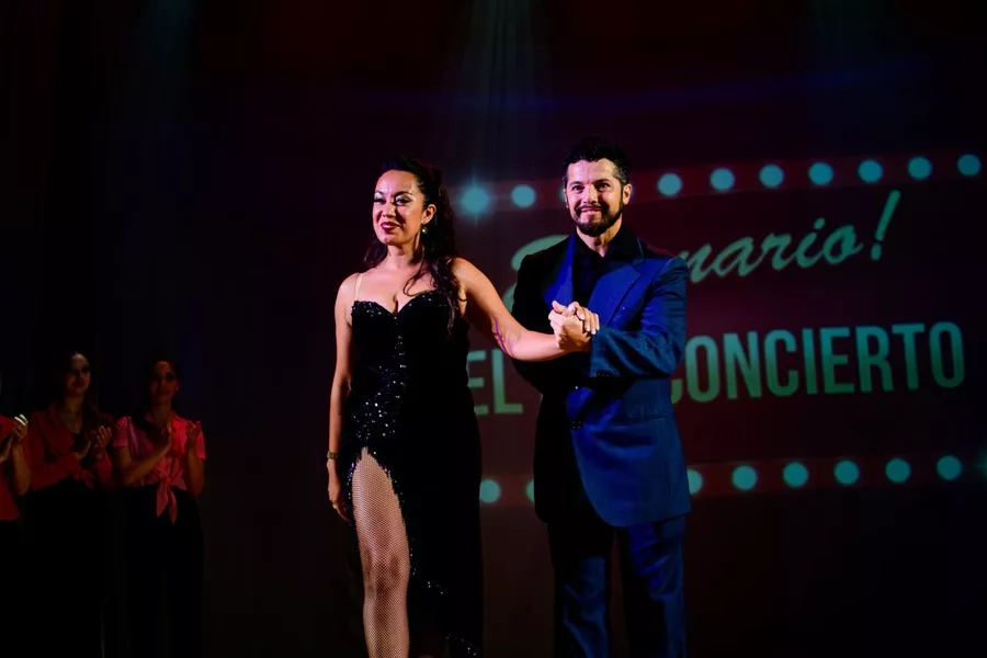 Es la imagen de una bailarina y un bailarín que están vestidos como sus personajes: de traje y vestido