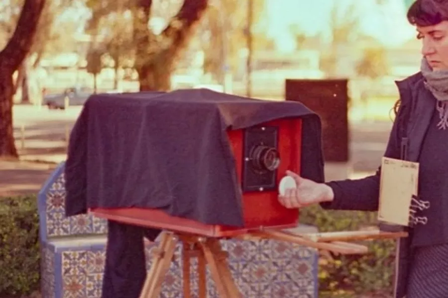 Es la imagen de una fotográfa preparando una cámara antigua para sacar una fotografía
