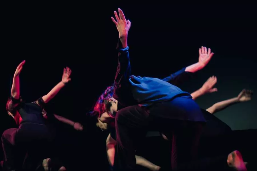 Es la imagen de un grupo de bailarinas y bailarines realizando una coreografía músical
