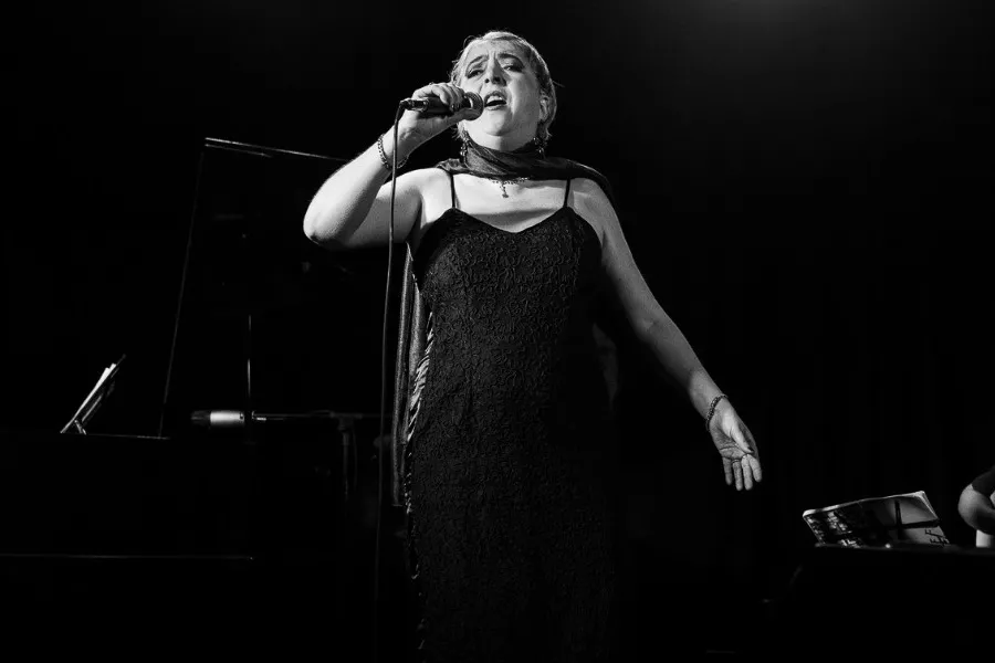 Es la imagen de una cantante cantando una canción. Tiene un vestido negro